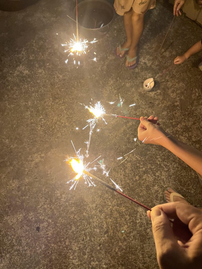 子どもが庭で手持ち花火をしている夜の様子